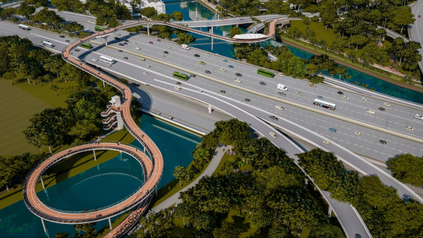 Aerial view of a highway with a pedestrian bridge looping over a river and roads.